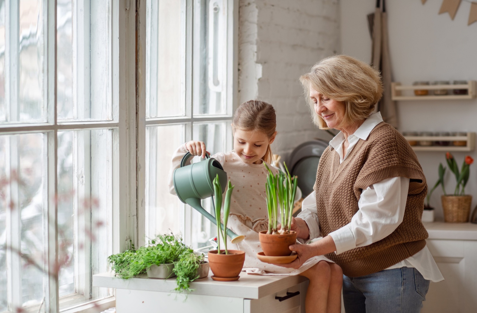 A smiling senior cares for potted herbs with their grandchild.
