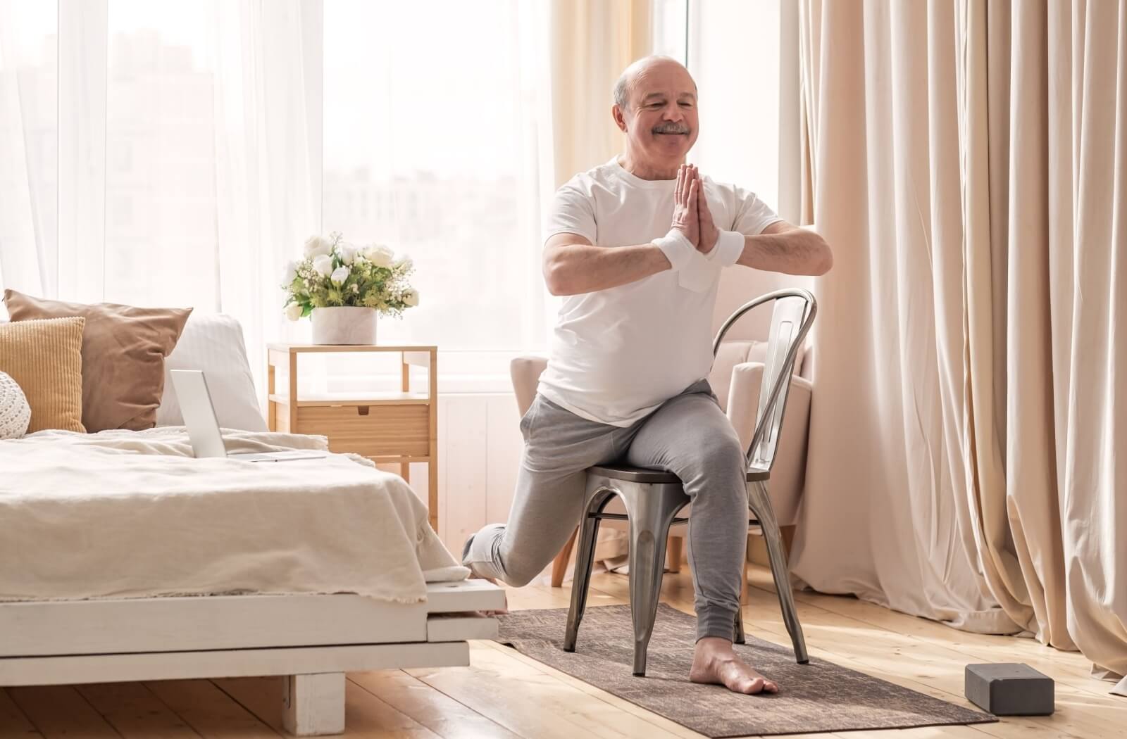 A smiling senior does chair yoga to stay physically active.