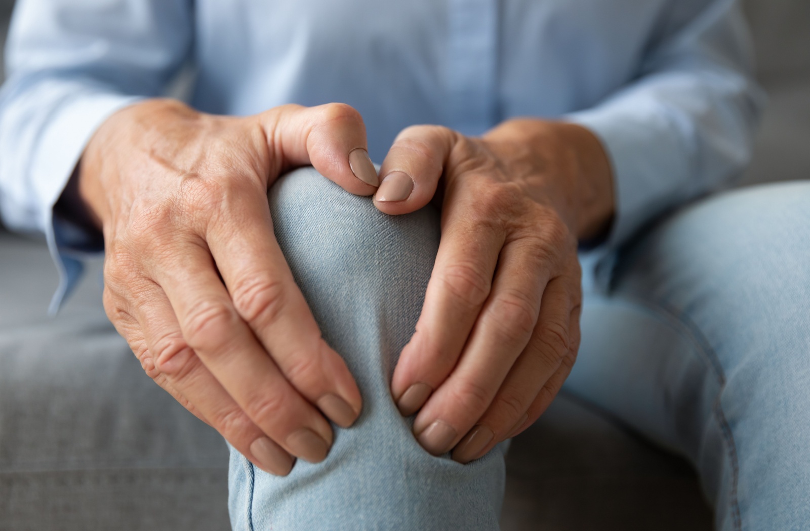 An older adult rubbing their right knee to lower their joint discomfort.