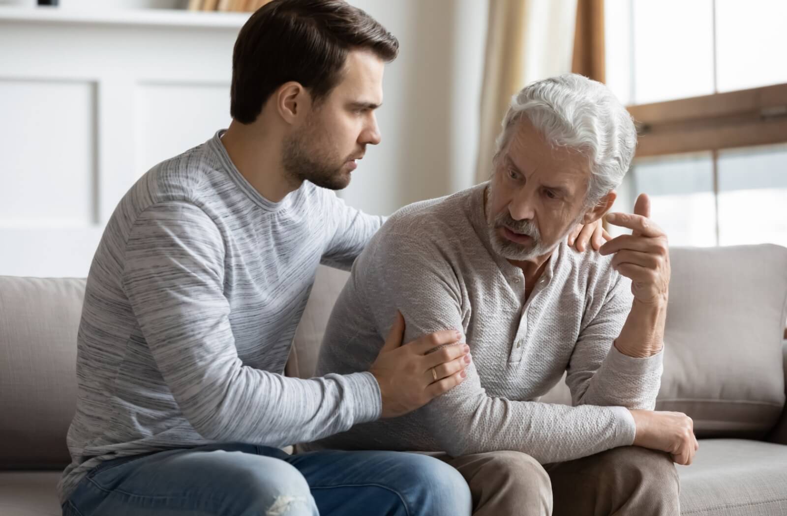 An adult child comforts their parent who is experiencing frustration trying to communicate.