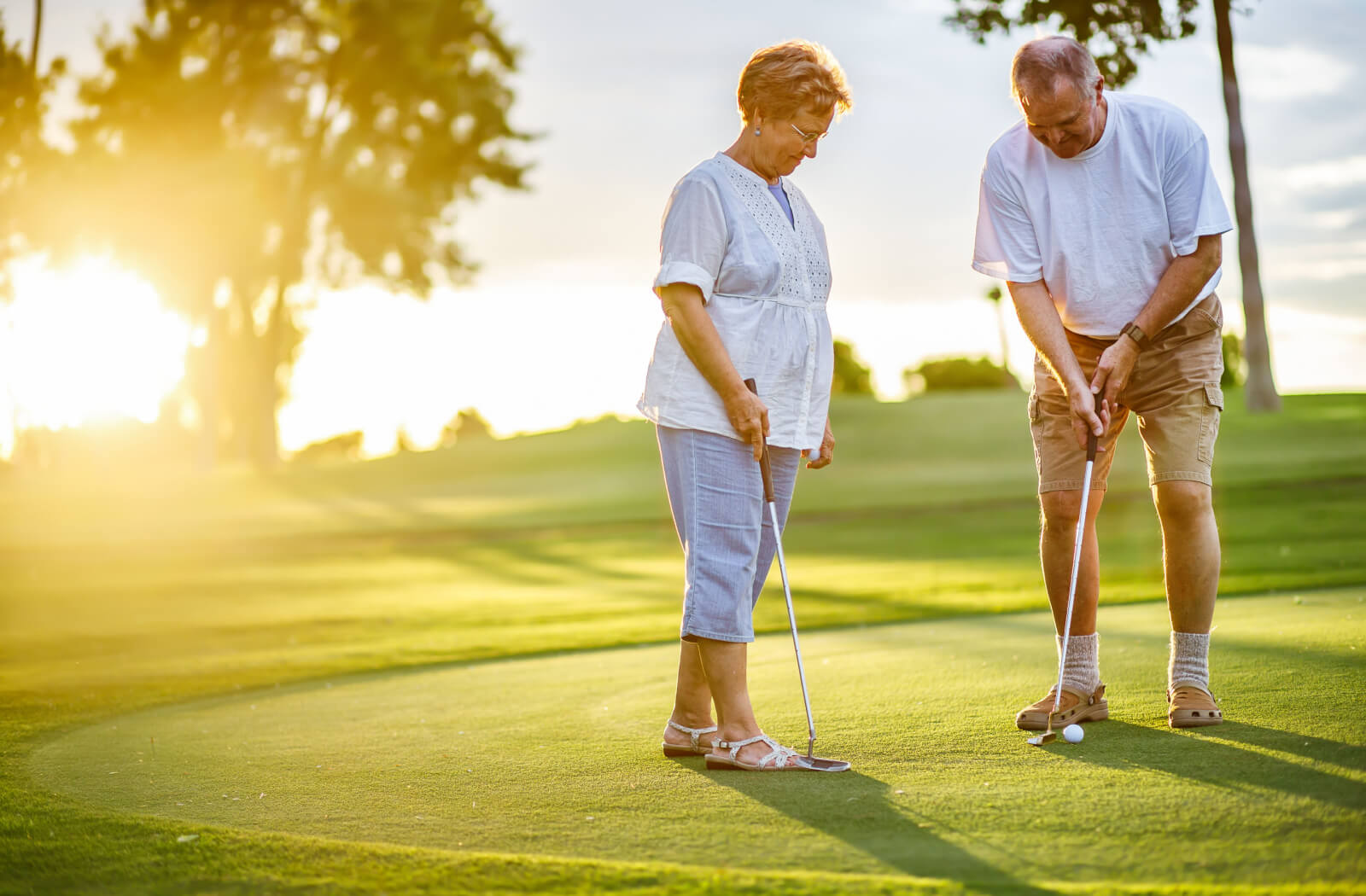 A senior couple playing golf on a sunny day.
