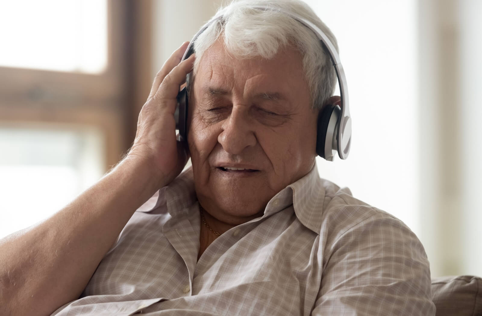 A senior with dementia listening to music using wireless headphones.