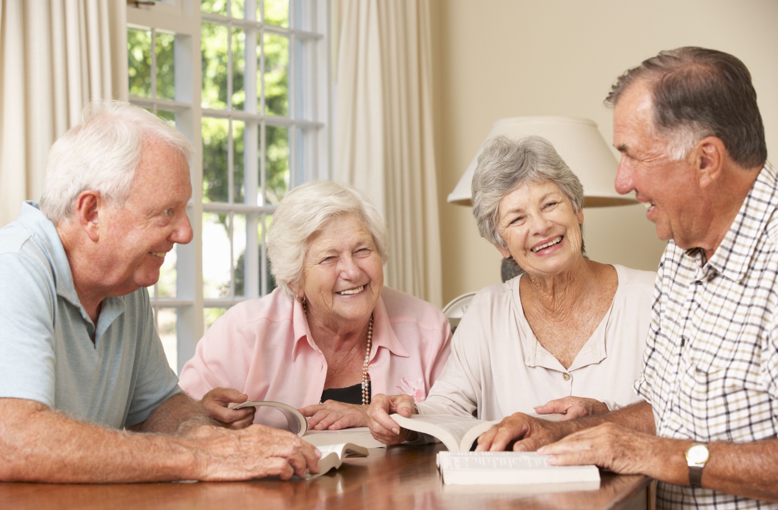 A happy group of seniors discusses their latest book during a book club meeting.